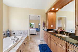 Full bath featuring double vanity, ensuite bathroom, a garden tub, recessed lighting, and light tile patterned floors