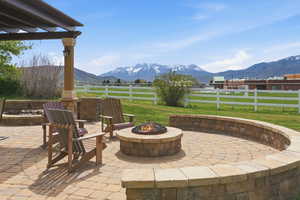 View of patio with a mountain view, an outdoor fire pit, a view of countryside, and a pergola