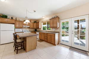 Kitchen with white appliances, french doors, a breakfast bar, a kitchen island, and wood finish cabinets