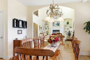 Dining space featuring suspended lighting, built in features, light wood-style flooring, and a glass covered fireplace