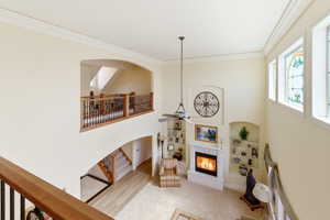 Living area featuring ceiling fan, a high ceiling, crown molding, a glass covered fireplace, and arched walkways