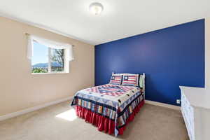 Bedroom with light colored carpet and an accent wall