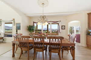 Dining area with arched walkways, light wood-style flooring, a chandelier, and healthy amount of natural light