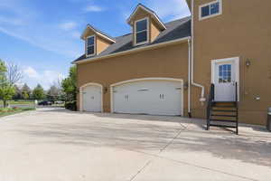 View of home's exterior featuring a shingled roof, driveway, stucco siding, and an attached garage