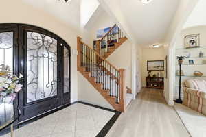 Foyer with arched walkways, light wood-style flooring, and inlaid floor details