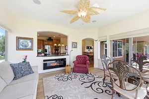 Living room with plenty of natural light, arched walkways, ceiling fan, and light wood-style flooring
