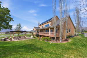Rear view of house with a fire pit, a patio area, solar panels, and roof with shingles