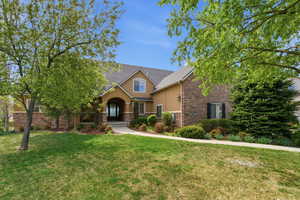 View of front of property with a front lawn, stucco siding, and stone siding
