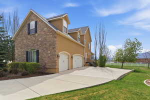 View of property exterior featuring stucco siding, concrete driveway, stone siding, and an attached garage