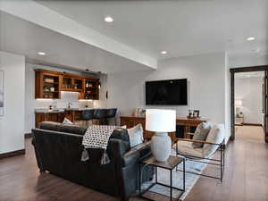 Living area with dark wood-type flooring, recessed lighting, and wet bar