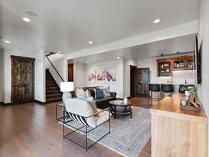 Living area featuring bar with sink, light wood-style flooring, and recessed lighting