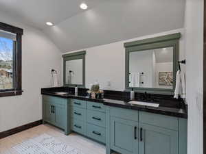 Bathroom featuring double vanity, lofted ceiling, and recessed lighting