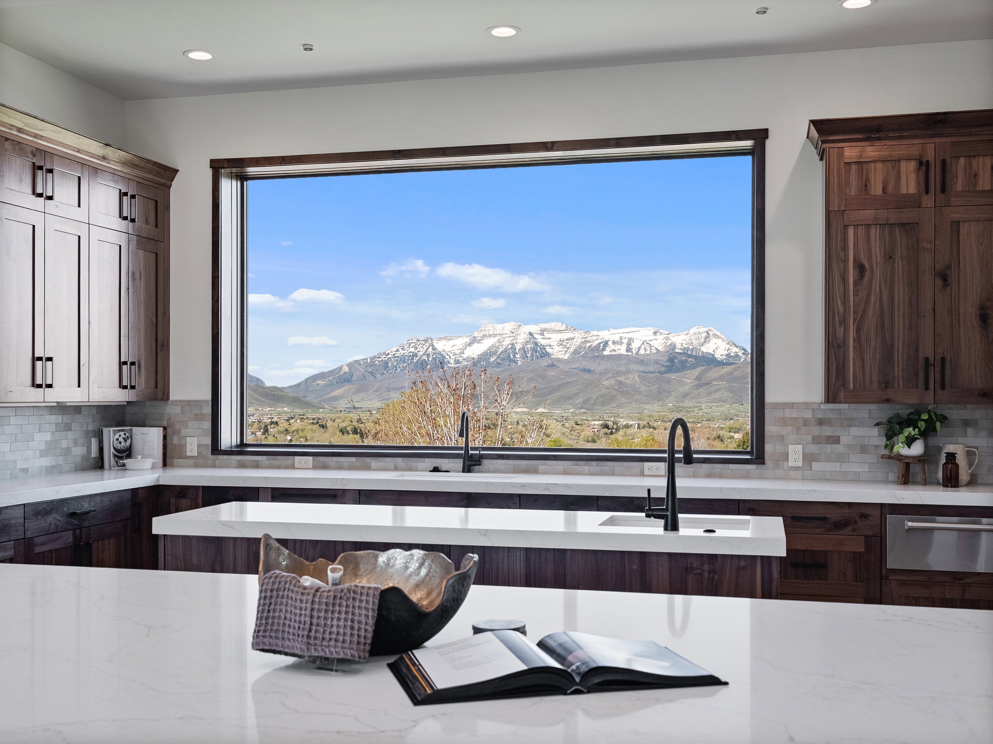 Expansive kitchen window framing snow-capped mountains