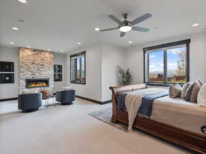 Carpeted bedroom with a ceiling fan, recessed lighting, and a stone fireplace