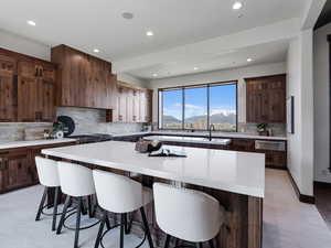 Kitchen featuring a breakfast bar, a kitchen island, dark wood finish cabinetry, light stone counters, and recessed lighting