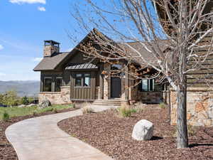 View of front of home featuring board and batten siding, stone siding, roof with shingles, a chimney, and a mountain view