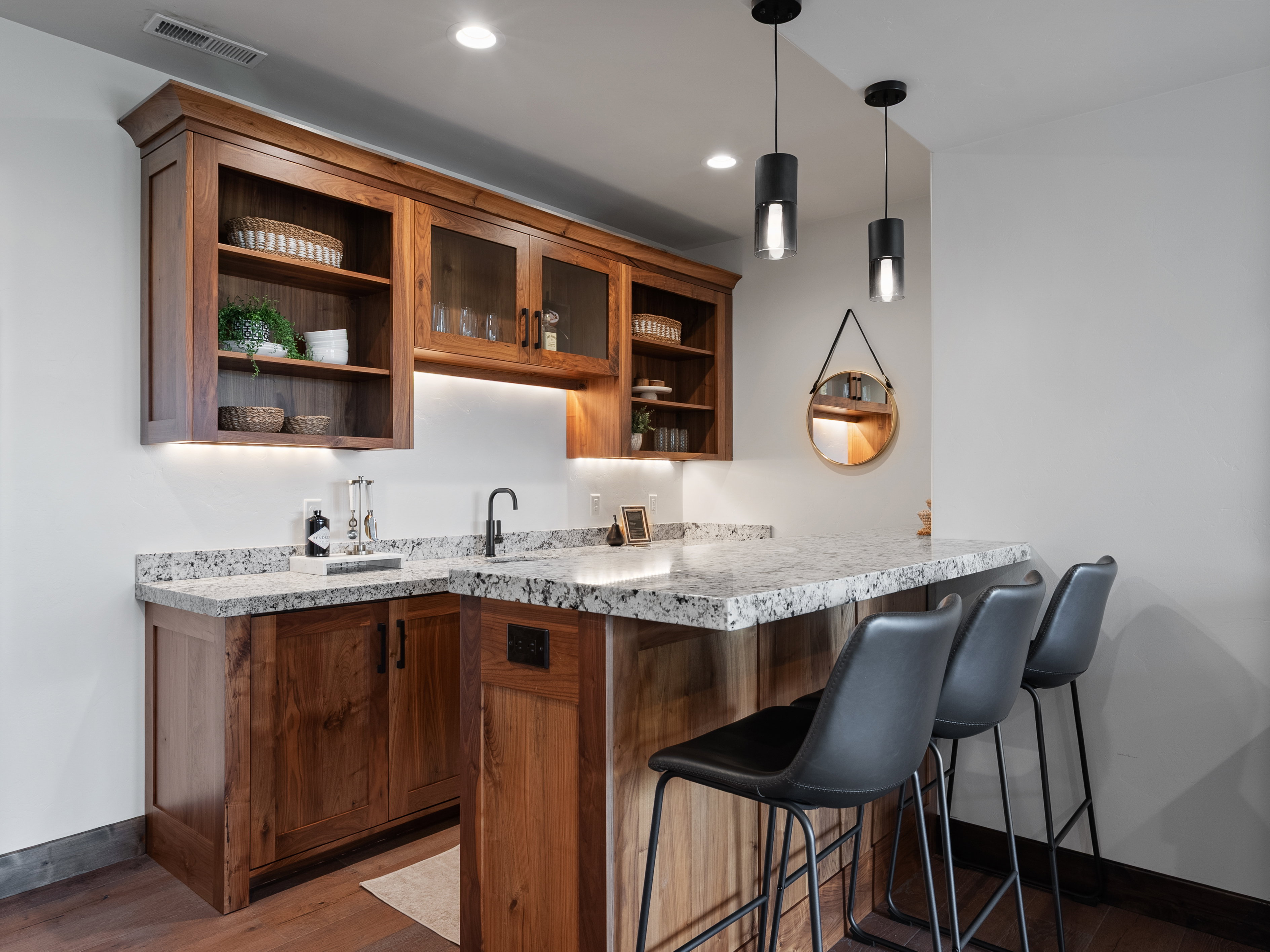 Bar area with open shelves, dark wood finished floors, pendant lighting, light stone countertops, and wood finish cabinetry