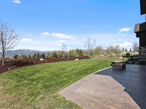 View of green lawn with an outdoor fire pit and a mountain view