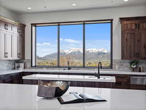 Kitchen featuring backsplash, dark wood finish cabinetry, light stone counters, and recessed lighting