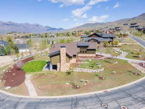 View of front of property with solar panels, a mountain view, stone siding, a front lawn, and a chimney