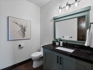 Half bathroom with vanity and dark wood finished floors