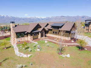 View of front of house with stone siding, a chimney, board and batten siding, a mountain view, and a shingled roof