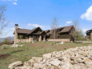 View of front of house featuring stone siding, a chimney, and a shingled roof