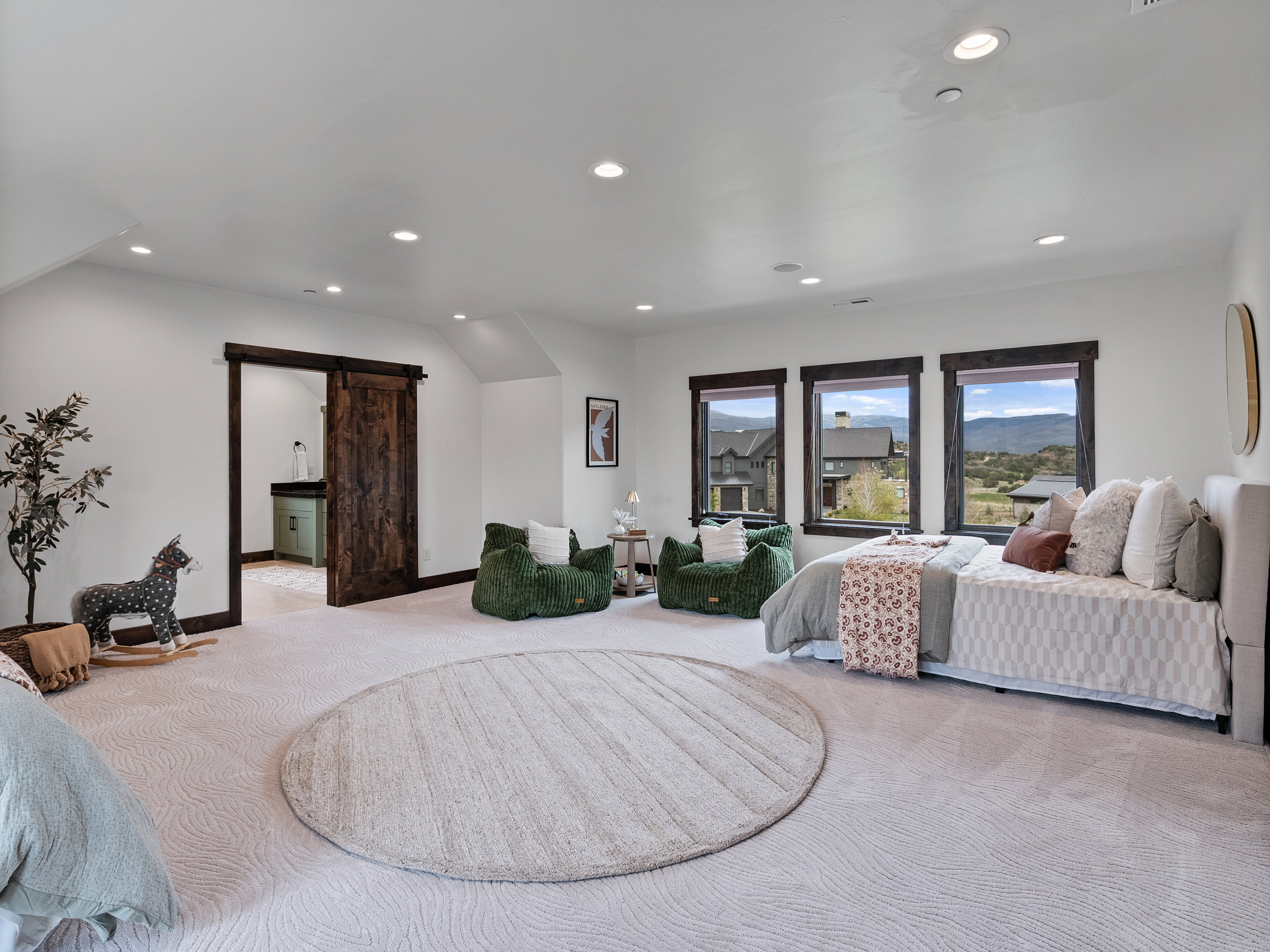 Bedroom with a barn door, light colored carpet, recessed lighting, and ensuite bathroom