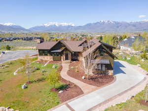 View of front of property featuring stone siding, driveway, board and batten siding, a mountain view, and covered porch