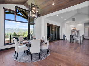 Dining room with hanging lights, a mountain view, hardwood / wood-style flooring, and a high wood ceiling
