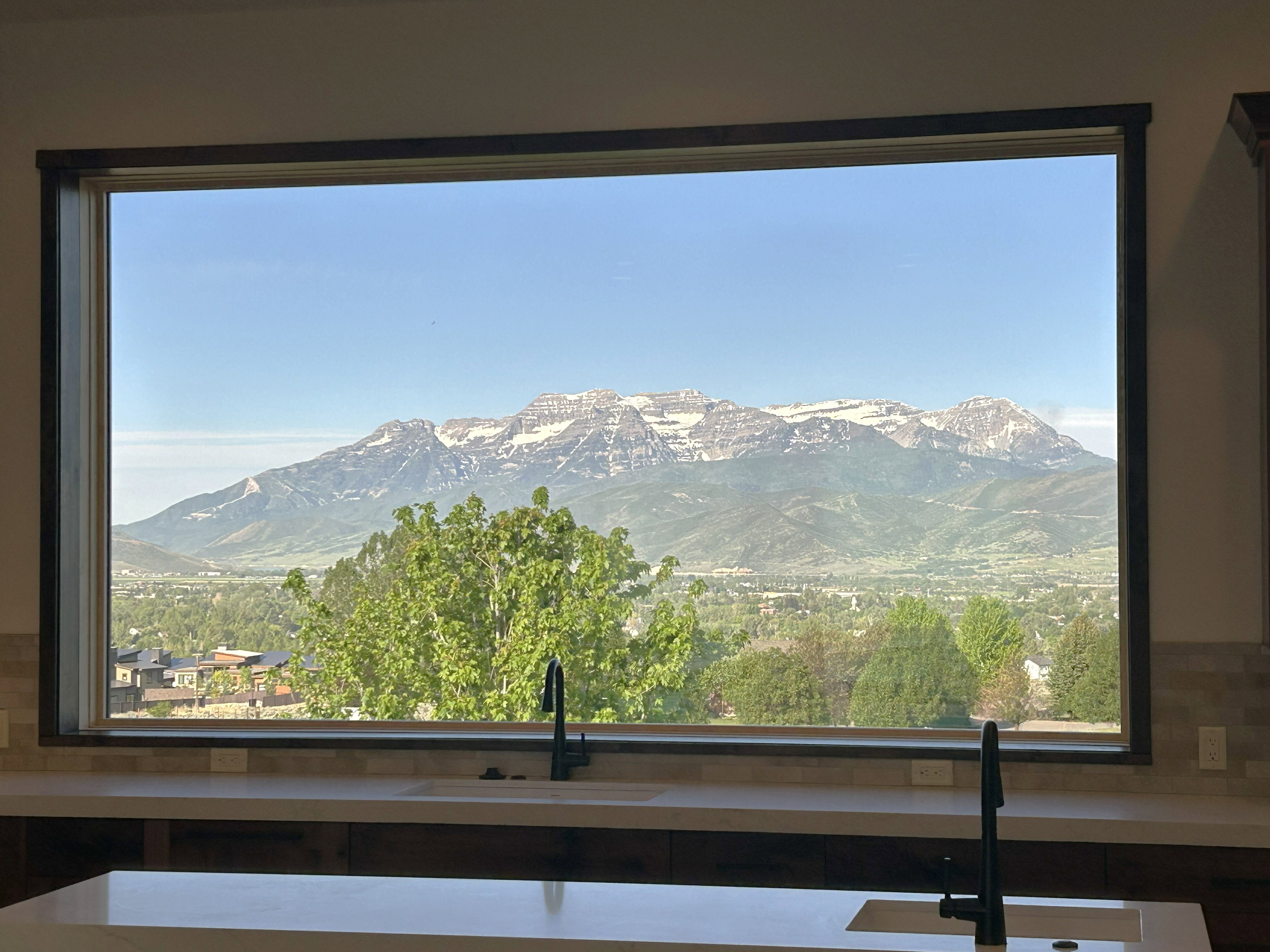 Expansive window framing a mountain range with snow-capped peaks