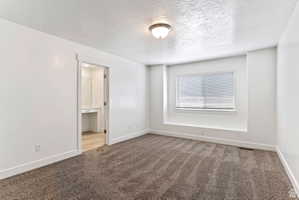 Empty room featuring a textured ceiling and carpet