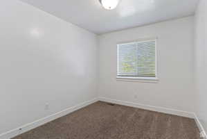 Spare room with dark colored carpet and a textured ceiling