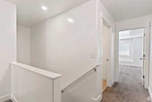 Hallway featuring an upstairs landing and carpet floors