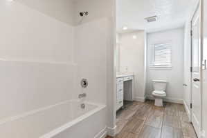 Full bathroom featuring washtub / shower combination, a textured ceiling, and vanity