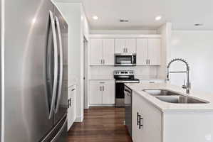 Kitchen featuring stainless steel appliances, dark wood-style floors, light stone countertops, recessed lighting, and white cabinets