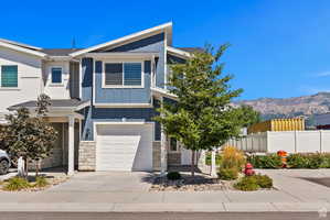Contemporary house featuring a garage, board and batten siding, driveway, and stone siding