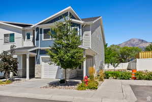 View of front of home with stone siding, an attached garage, a mountain view, and driveway