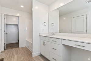 Full bath featuring vanity, a spacious closet, a bathtub, and recessed lighting