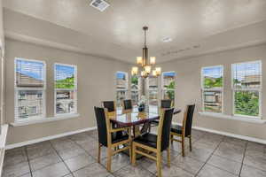 Dining space with suspended lighting, light tile patterned flooring, and a textured ceiling