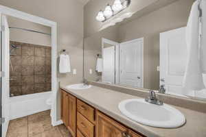 Bathroom featuring double vanity, bathtub / shower combination, and light tile patterned flooring