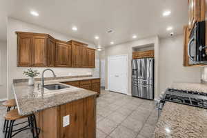 Kitchen with a peninsula, stainless steel appliances, light stone countertops, a kitchen breakfast bar, and recessed lighting