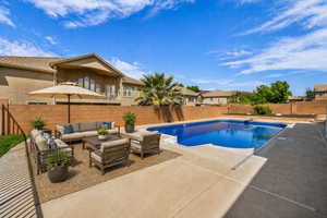 View of swimming pool featuring patio surround, a fenced backyard, an outdoor lounge area, and a diving board