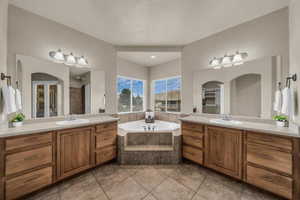 Full bathroom with two vanities, a bath, light tile patterned flooring, and a shower stall