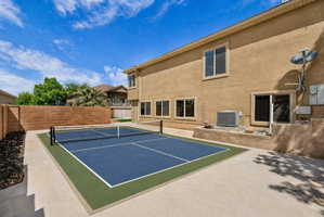 View of tennis court with a patio