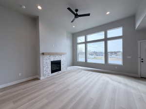 Unfurnished living room with ceiling fan, light wood-style floors, a fireplace, and recessed lighting