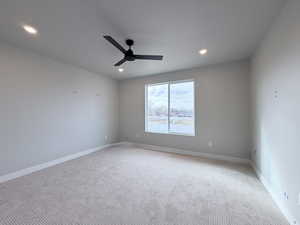 Empty room featuring light colored carpet, ceiling fan, and recessed lighting