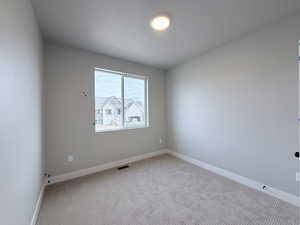 Empty room featuring light carpet and baseboards
