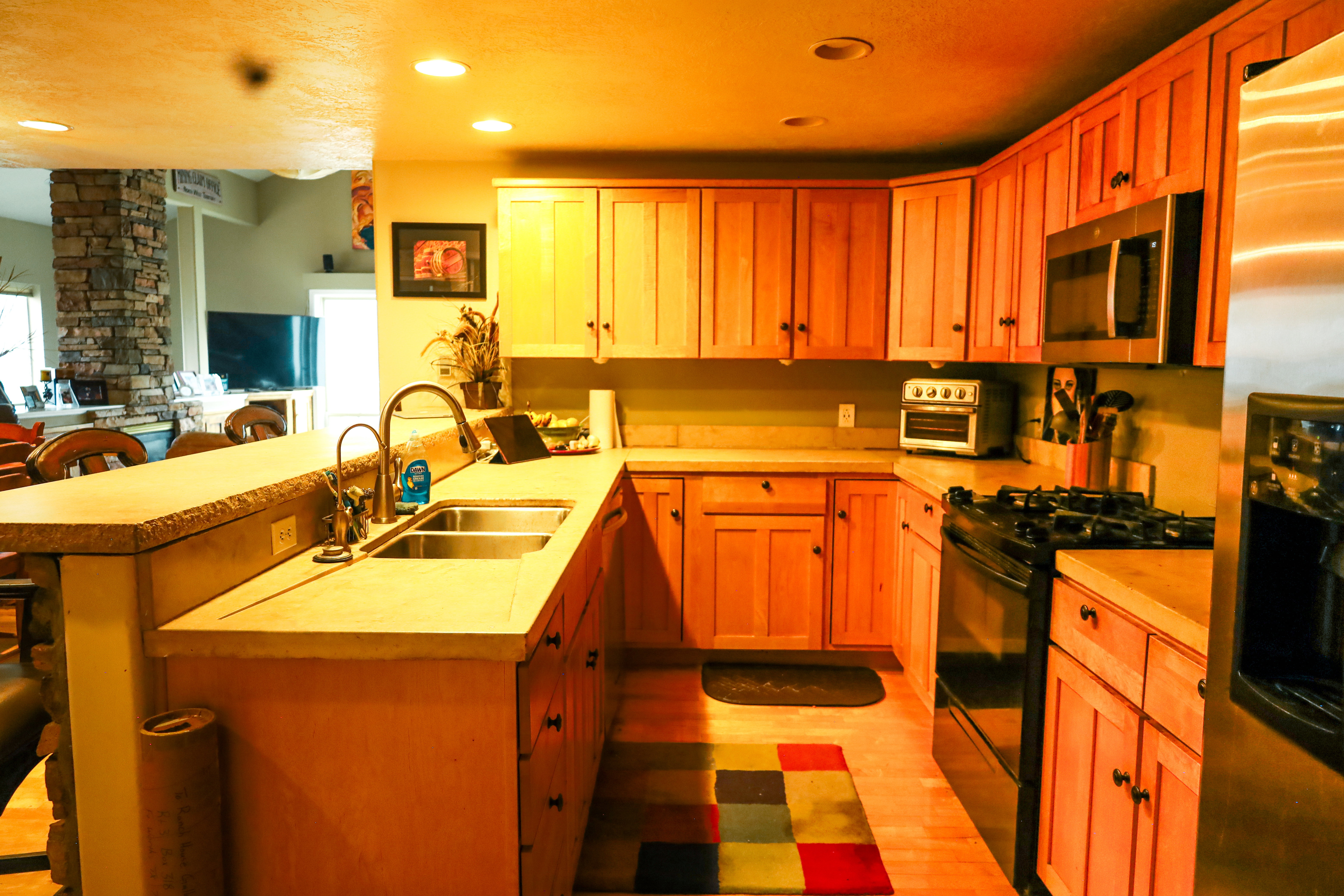 Kitchen featuring a peninsula, light countertops, stainless steel appliances, light wood-style floors, and a breakfast bar