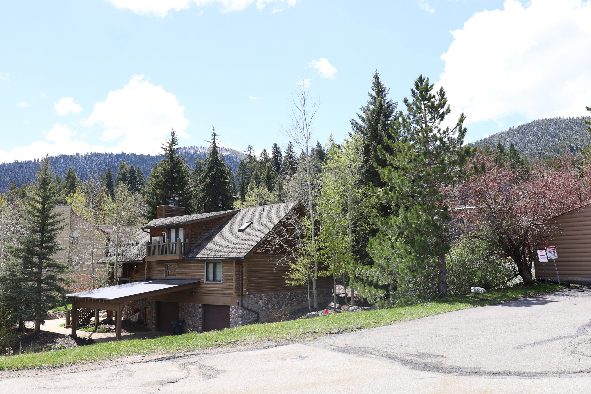 View of front of house with a chimney, a mountain view, a wooded view, stone siding, and a balcony